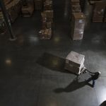 Warehouse worker using a manual pallet jack to move some products in a distribution warehouse.